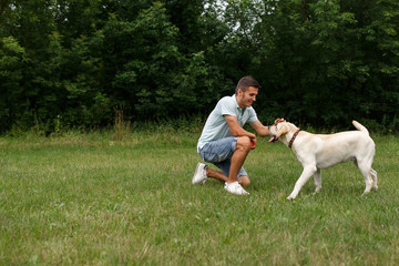 Happy young man is playing with dog Labrador