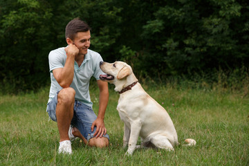 Friendship of man and dog. Happy young man sitting with his friend - dog Labrador