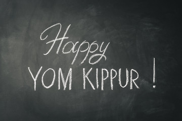 Inscription Happy Yom Kippur on chalkboard background.