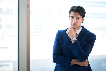 Fototapeta premium Young handsome businessman standing at the window 