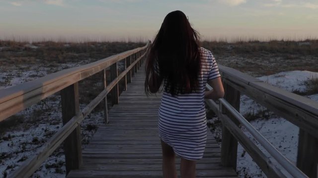 Woman walking on boardwalk to beach