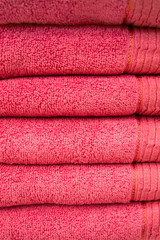 Dark pink bathroom towels in stack, spa concept