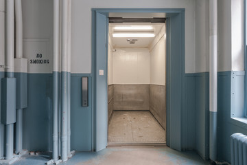 Open freight elevator in blue and white bay of office building