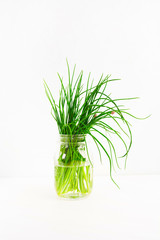 Glass jar with fresh green onion on light background