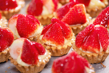 Close up of delicious tartlets with fresh strawberries and vanilla cream .
