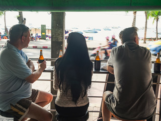 Rear view of three people in a bar drinking beer