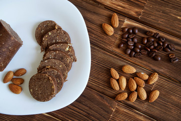 Almond nuts, coffee grains and chocolate pastry sausage on a wooden surface