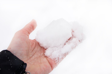 Female hand holding melting white snow in winter on white background. Cold weather