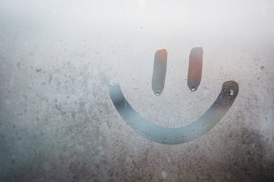 funny smiley face painted on a fogged window. drawing on a fogged window