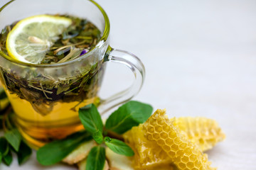 herbal tea with a slice of lemon and fresh fruit in a clear glass mug. honey in honeycombs.