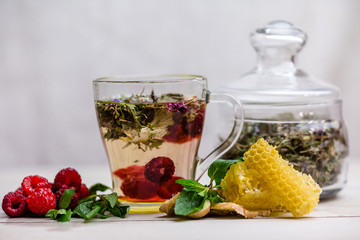 herbal tea with a slice of lemon and fresh fruit in a clear glass mug. honey in honeycombs.