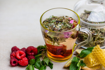 herbal tea with a slice of lemon and fresh fruit in a clear glass mug. honey in honeycombs.