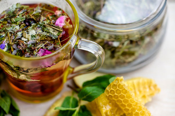 herbal tea with a slice of lemon and fresh fruit in a clear glass mug. honey in honeycombs.
