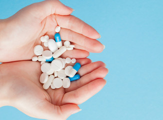Woman's holding cupped hand full of pills, view from above