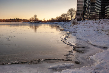 Obraz premium Toronto, CANADA - February 1th, 2019: Panoramic Canadian winter landscape near Toronto, beautiful frozen Ontario lake at sunset. Scenery with winter trees, water and blue sky.