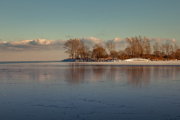 Toronto, CANADA - February 1th, 2019: Panoramic Canadian winter landscape near Toronto, beautiful frozen Ontario lake at sunset. Scenery with winter trees, water and blue sky.