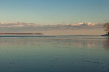 Toronto, CANADA - February 1th, 2019: Panoramic Canadian winter landscape near Toronto, beautiful frozen Ontario lake at sunset. Scenery with winter trees, water and blue sky.