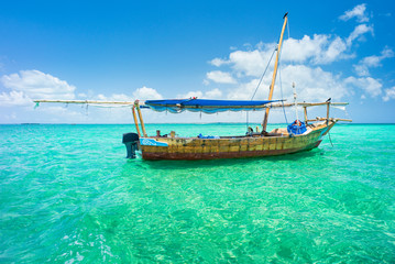 Fototapeta na wymiar alone wooden boat on emerald sea of Indian ocean in Zanzibar in Tanzania