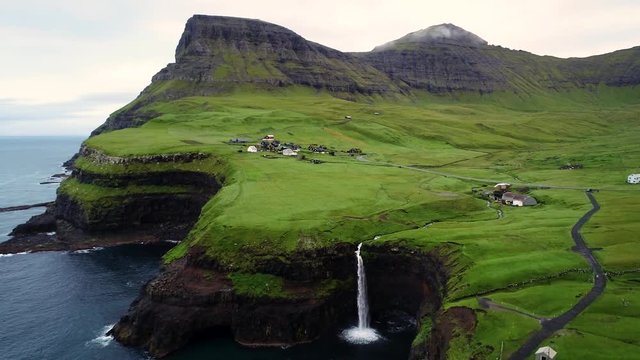 Aerial view of M&uacute;lafossur waterfall near a small village, Faroe island.