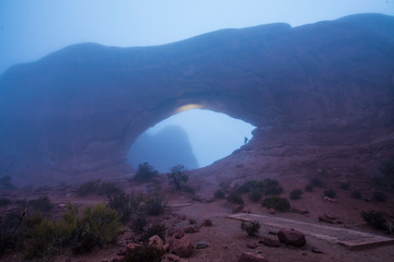 One man stands alone under an arch on a foggy morning in Utah