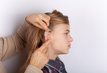 Hearing aid inserting in a young girl's ear