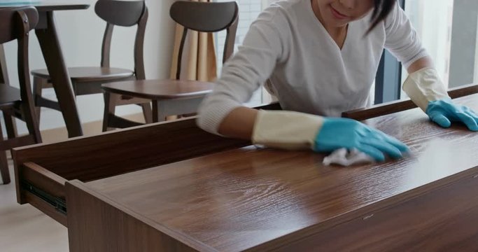 Asian Woman clean the TV cabinet at home for spring clean