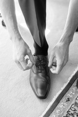 A groom fastening his lace on his shoes