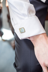 A close up of a grooms cufflink on his white shirt