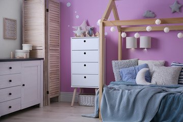Child's room interior with comfortable bed and garland