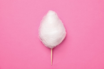 Stick with yummy cotton candy on color background, top view