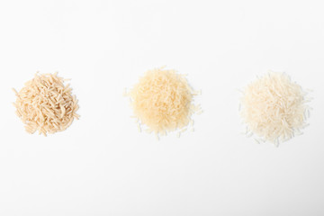 Different types of uncooked rice on white background, top view