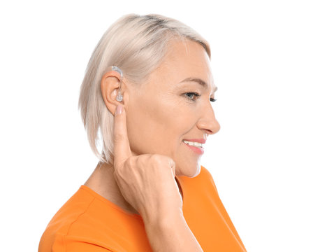 Mature woman adjusting hearing aid on white background