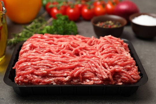 Plastic container with minced meat on kitchen table, closeup