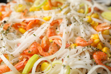 Rice noodles with shrimps and vegetables as background, closeup