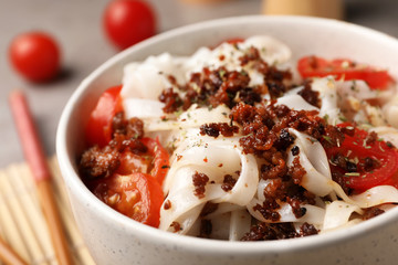 Bowl with rice noodles, meat and tomatoes, closeup