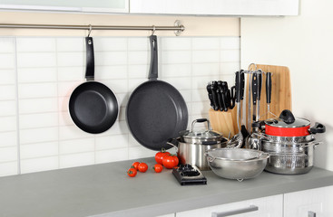Set of clean cookware and utensils on table in modern kitchen