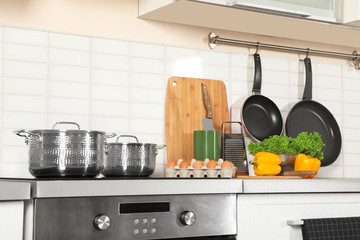 Set of clean cookware, utensils and products on table in modern kitchen