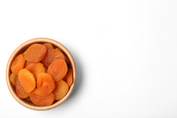 Wooden bowl of dried apricots on white background, top view with space for text. Healthy fruit