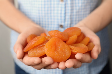 Woman holding handful of dried apricots, closeup. Healthy fruit