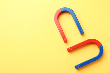 Red and blue horseshoe magnets on color background, top view with space for text