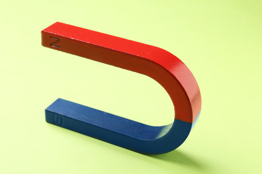 Red and blue horseshoe magnet on color background