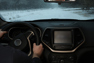 Young man driving car along winter forest, closeup