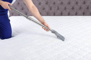Man disinfecting mattress with vacuum cleaner, closeup. Space for text