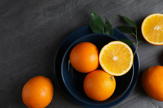 Fresh oranges and bowl on grey table, top view with space for text