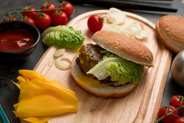 Homemade hamburger with fresh vegetables served on a wooden tray. Homemade preparing concept.