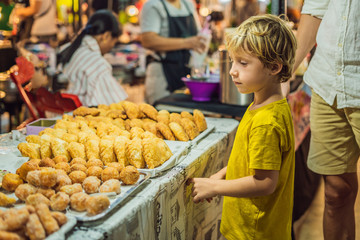 Dad and son are tourists on Walking street Asian food market