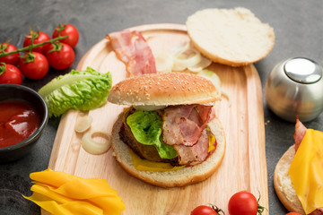 Homemade hamburger with fresh vegetables served on a wooden tray. Homemade preparing concept.