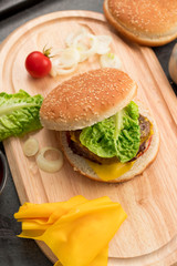 Homemade hamburger with fresh vegetables served on a wooden tray. Homemade preparing concept.