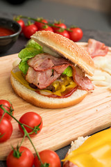 Homemade hamburger with fresh vegetables served on a wooden tray. Homemade preparing concept.