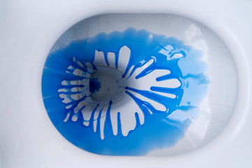 Ceramic toilet bowl with blue liquid detergent